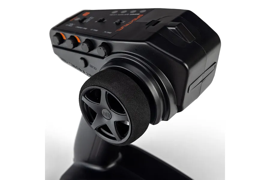 Close-up studio shot of the steering wheel and top control panel of a black Spektrum RC transmitter against a white background.