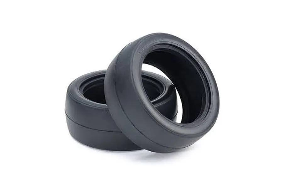 Two black rubber racing slick RC tyres shown angled against a clean white studio background.