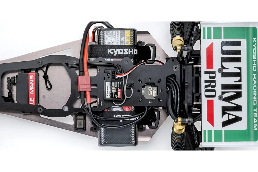 Top-down studio shot of the electronics layout and chassis deck of the Kyosho Ultima Pro RC buggy.