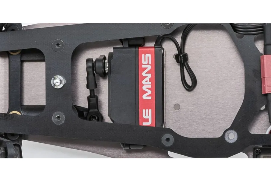 Close-up of a Le Mans steering servo mounted on the metal chassis of a Kyosho Ultima Pro RC buggy.