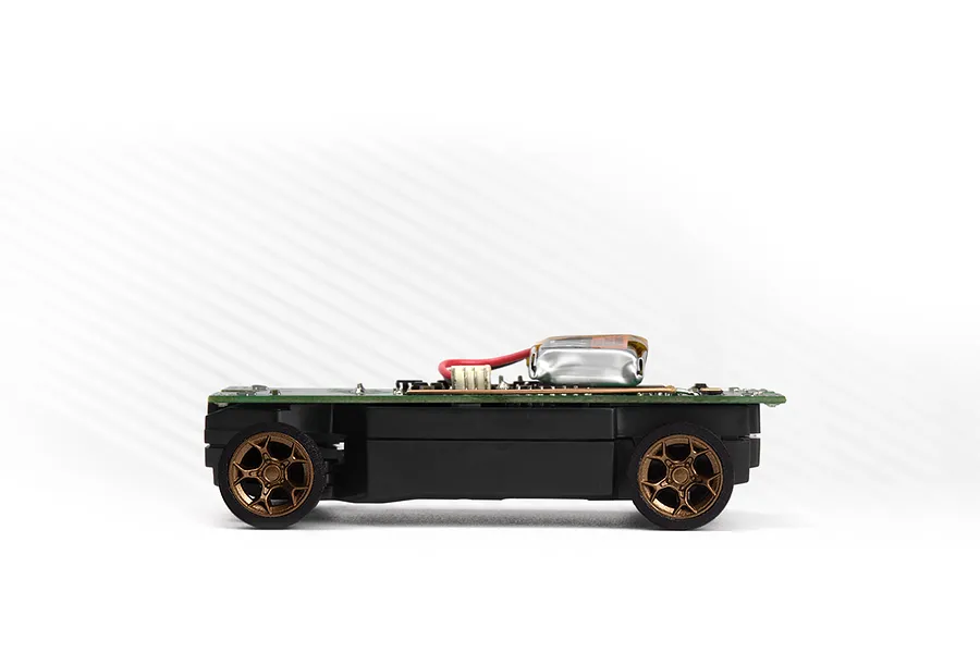 Side view of an RC car chassis with circuit board, battery, and bronze wheels on a white background.