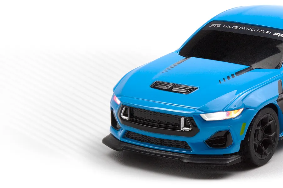 Close-up of the front end of a blue HPI Nano-TTR Ford Mustang RC car with illuminated headlights against a white gradient background.