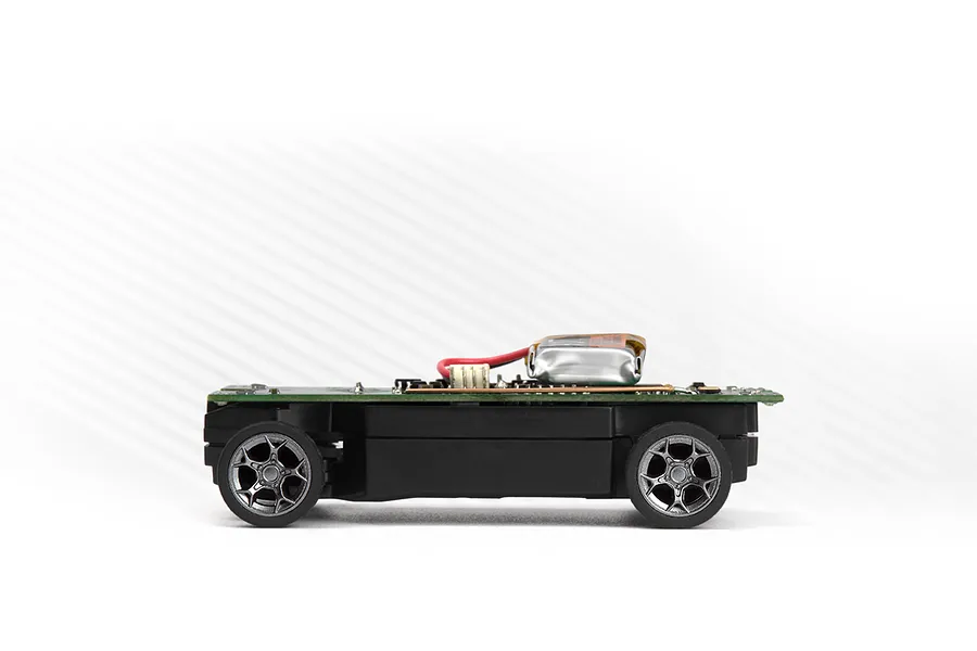 Side view of an RC car chassis with wheels, circuit board, and a small battery mounted on a white background.
