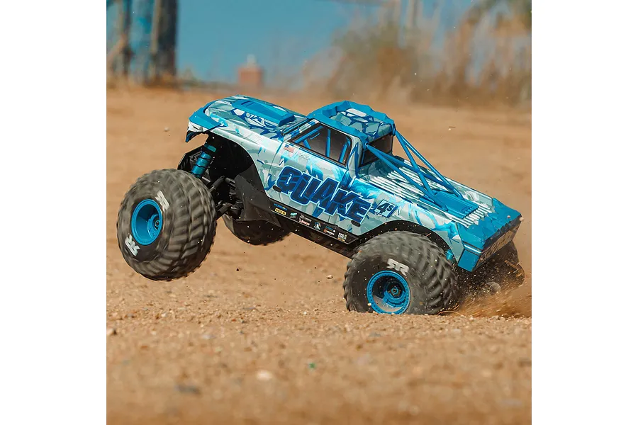 ARRMA Quake 4S RC monster truck in action kicking up dirt on an outdoor dirt track with a blue and white body shell.