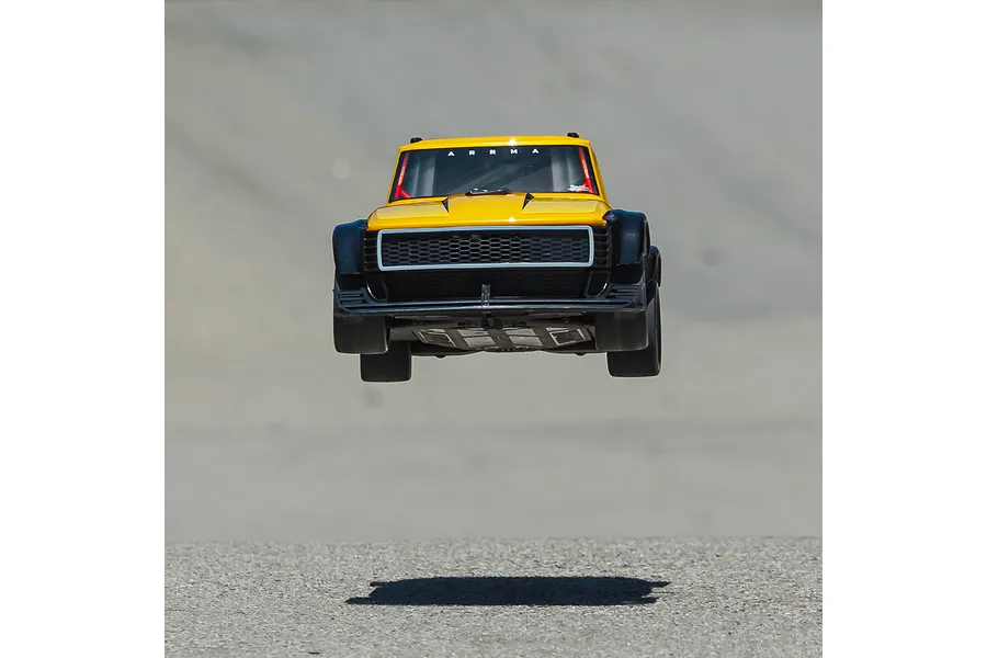 ARRMA Infraction 3S yellow RC street bash car jumping in the air over an asphalt surface.