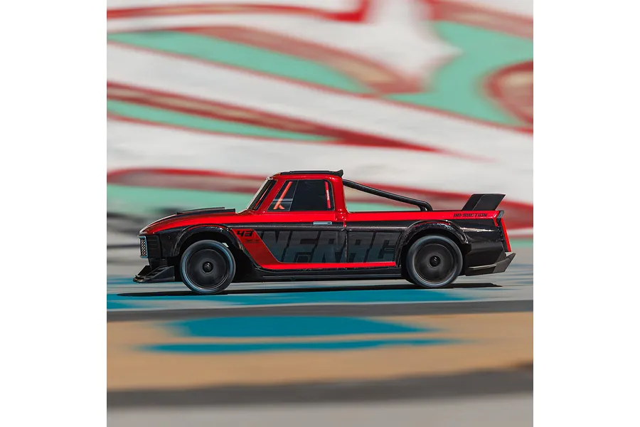 Side profile of a red and black ARRMA Infraction Grom RC car driving across an outdoor track.