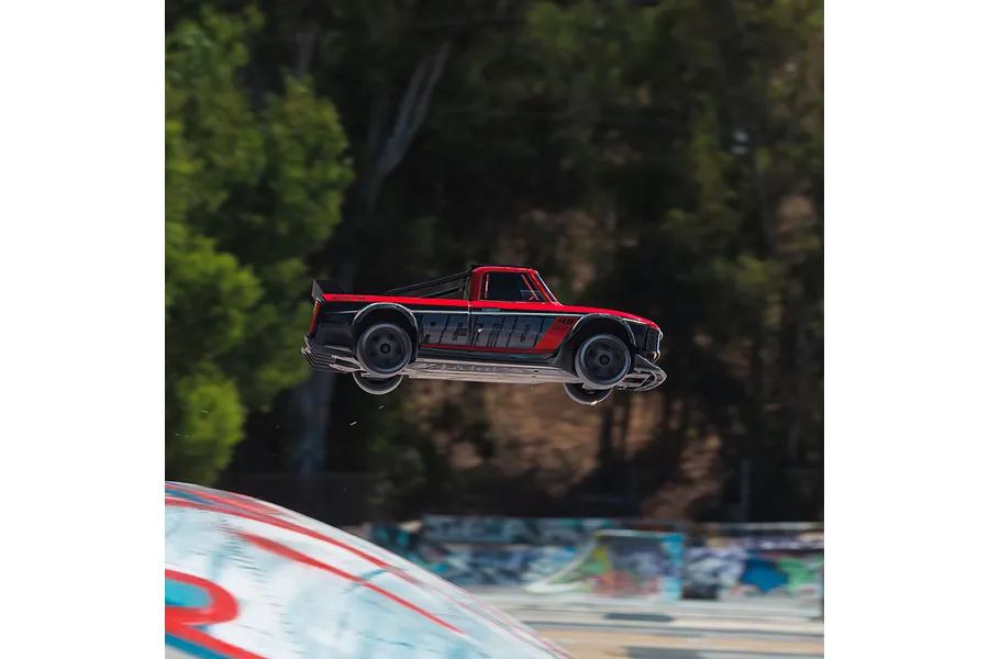 ARRMA Infraction Grom 3S RC car airborne outdoors after launching from a ramp.