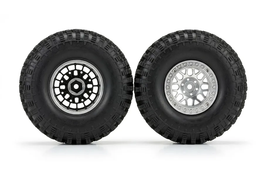 Two 1/10 scale RC crawler tyres mounted on silver beadlock wheels against a white background.