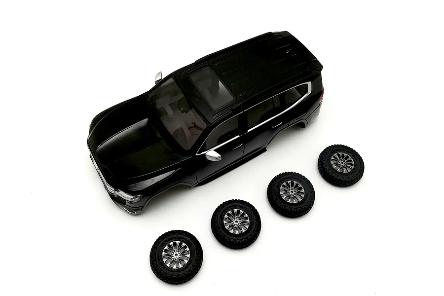 Black Kyosho Toyota Land Cruiser body shell shown from above on a white background alongside four matching wheels and tires.