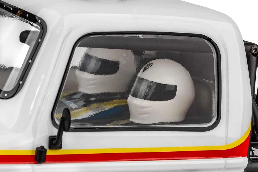 Close-up of the driver and co-driver helmets visible through the side window of the Element RC Gaterunner RC truck body.