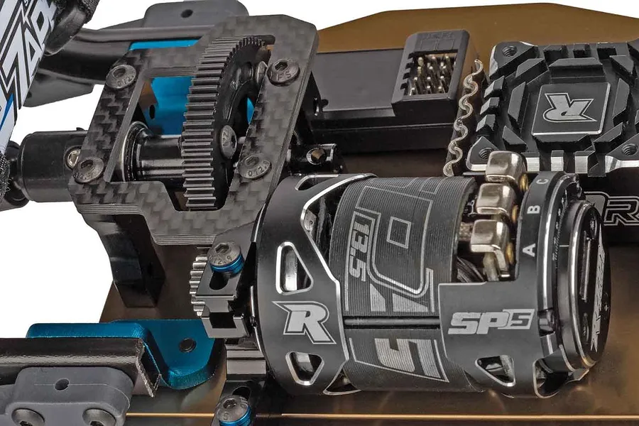 Close-up of Reedy electric motor and carbon fiber chassis components on an RC car.