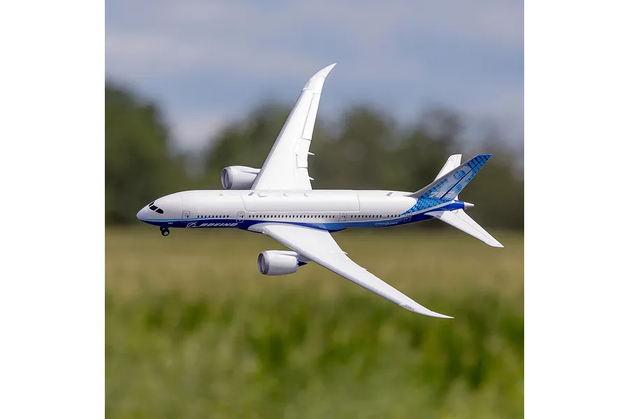 E-Flite Micro Boeing 787 Dreamliner RC airplane in flight against an outdoor field and sky background.