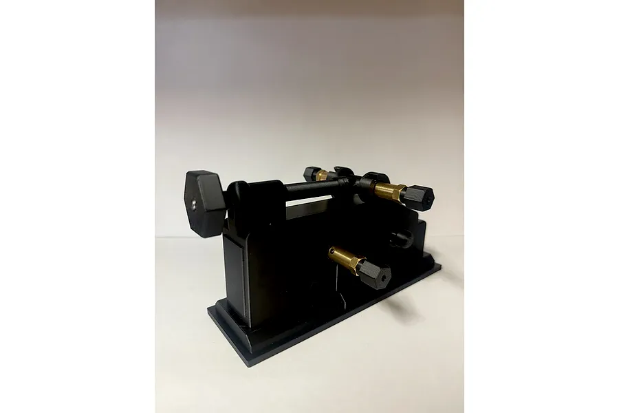 TK Racing tyre prep and break in machine featuring black and brass components against a white background.