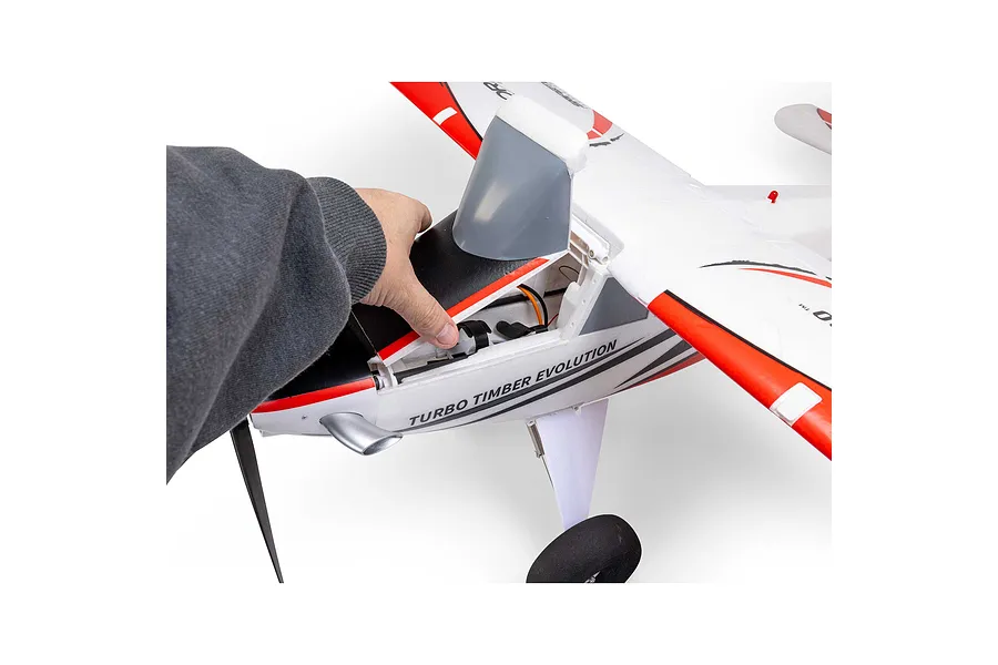 Person opening the top hatch of the white, red, and black E-Flite Turbo Timber Evolution RC plane fuselage.
