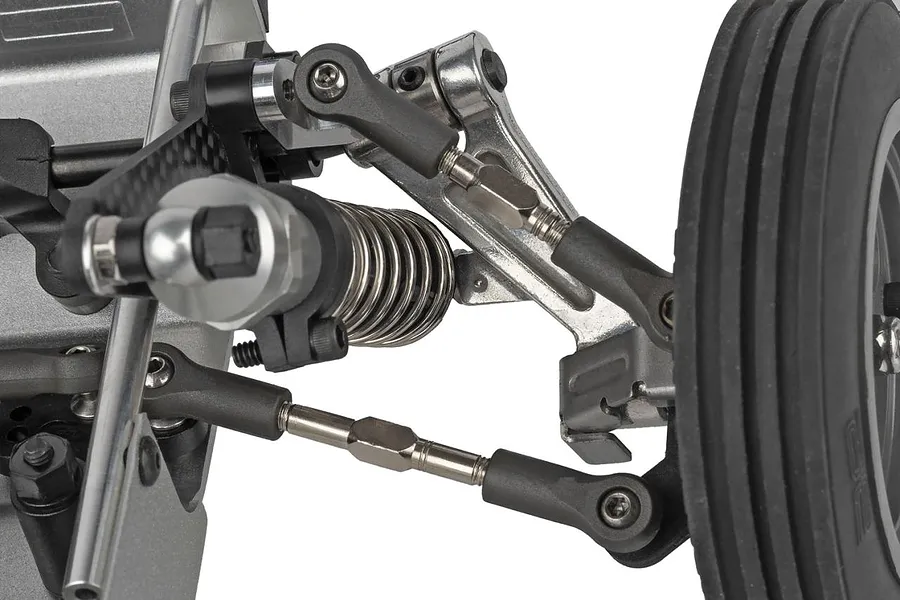 Close-up view of the front suspension, shock absorber, steering links, and wheel on a 1/10 scale RC buggy.
