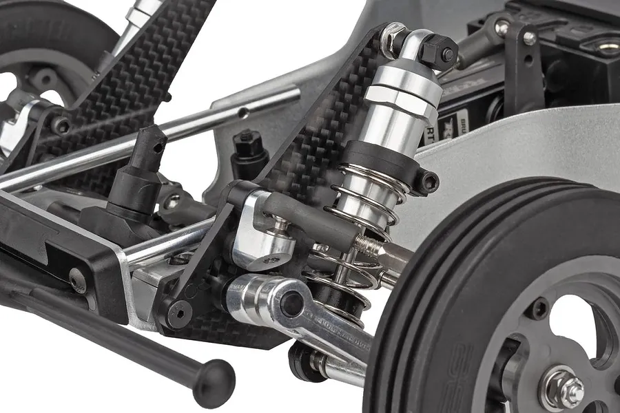Close-up of front suspension, carbon fibre shock tower, alloy shock absorber and linkages on a Team Associated RC car.
