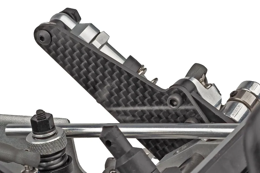 Close-up studio shot of a carbon fiber shock tower and suspension components on a Team Associated RC car.