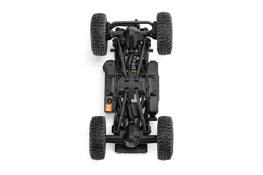 Underside chassis view of the Axial RC rock crawler showing suspension links, axles, and an on-off switch on a white background.