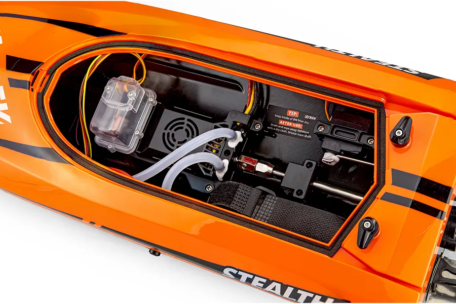 Top-down view of the interior compartment of the orange Atrek Stealth 25 RC boat, showing electronics and cooling hoses.