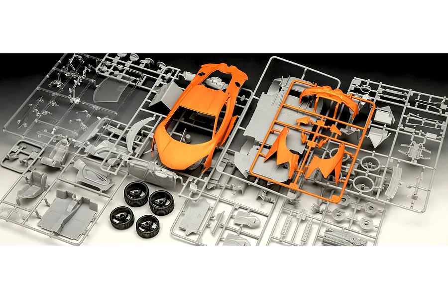 Unassembled plastic model kit parts for a Revell Lamborghini Revuelto, featuring orange body panels, grey components, and rubber tyres.