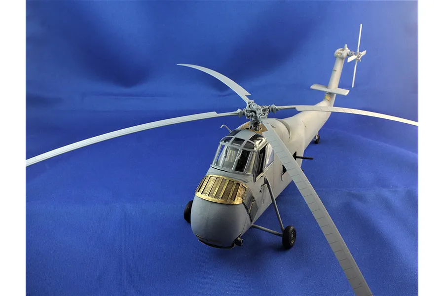 Completed Italeri 1/48 scale model helicopter in grey plastic against a blue background, showing detailed rotor blades and cockpit.