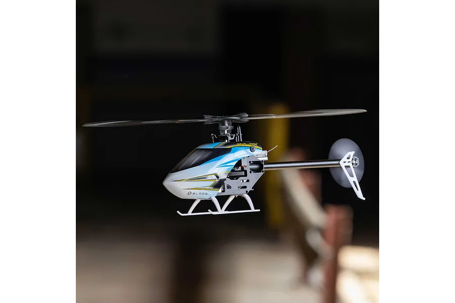 Blade Revolution 155 CP RC helicopter in flight against a dark indoor background