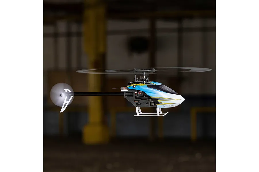 Blade Revolution 155 CP RC helicopter in flight against a dark indoor background.