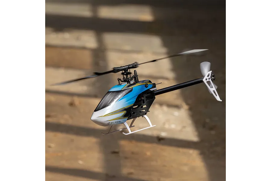 Blade Revolution 155 CP RC helicopter hovering indoors, featuring a blue, white, and black canopy and spinning rotor blades.