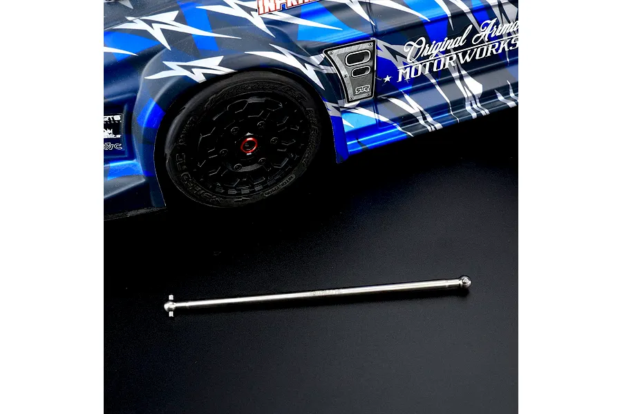 Method RC titanium centre rear driveshaft laid out on a dark surface in front of an RC car body.