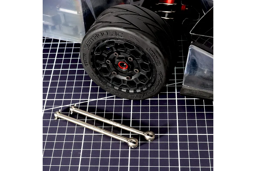 Method RC titanium CVD axle shafts laid out on a grid cutting mat in front of an RC car wheel and chassis.