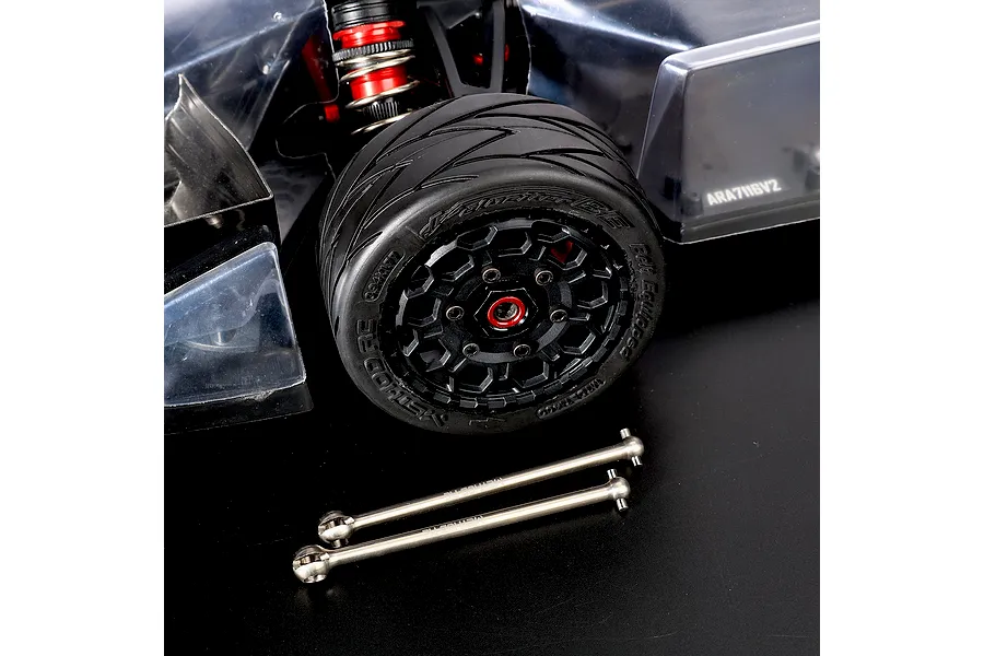 Two titanium CVD axle shafts laid in front of an RC car wheel and body assembly on a dark surface.
