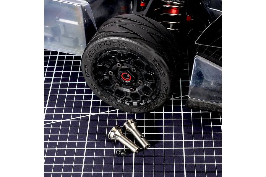 Method RC titanium CVD stub axles with associated hardware displayed in front of an RC car wheel on a cutting mat.