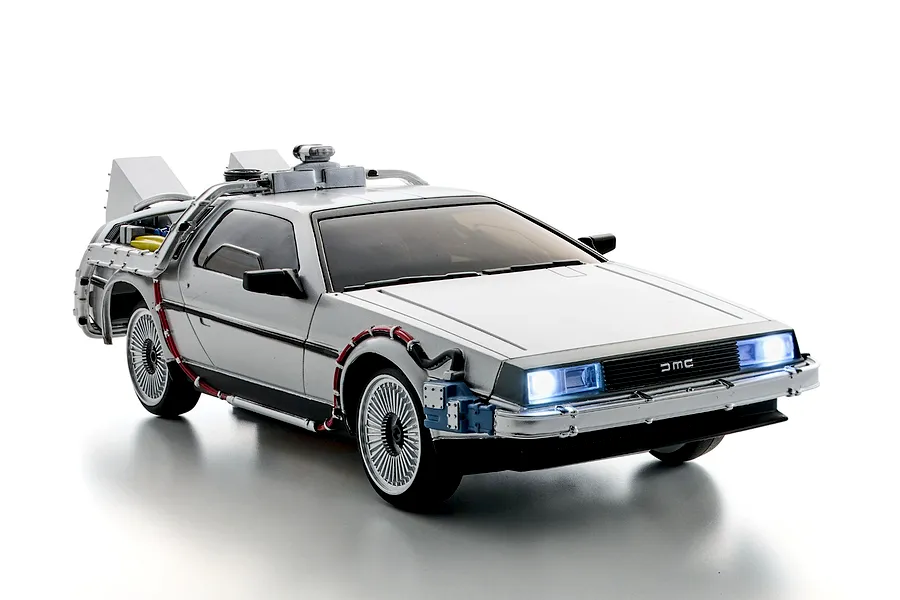 Kyosho First Mini-Z Back to The Future DeLorean RC car shown from a front-three-quarter studio angle with lit headlights.