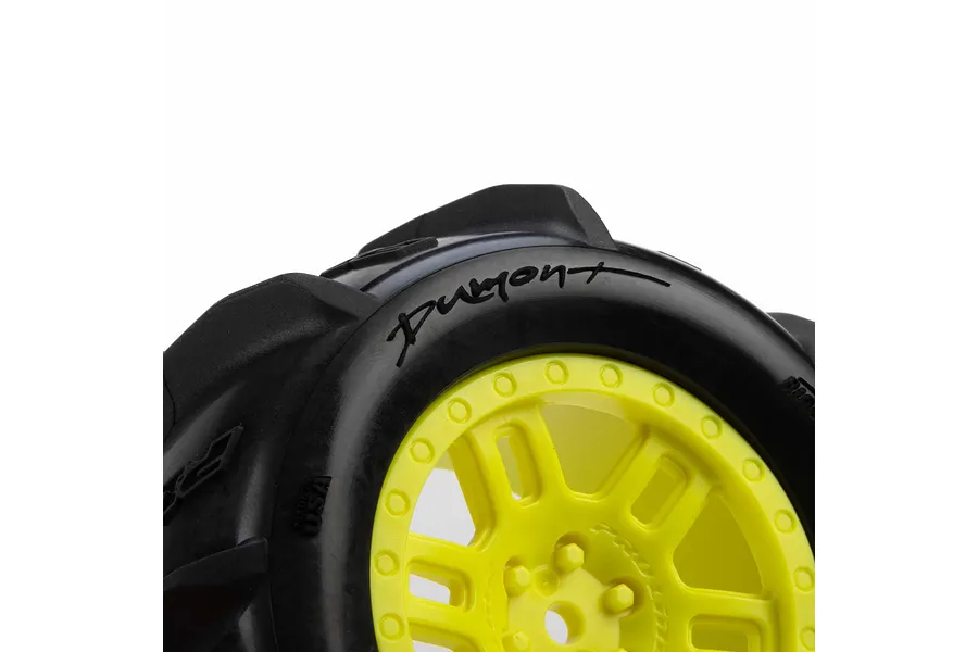 Close-up of a Pro-Line Dumont paddle tyre mounted on a yellow split-six wheel against a white background.