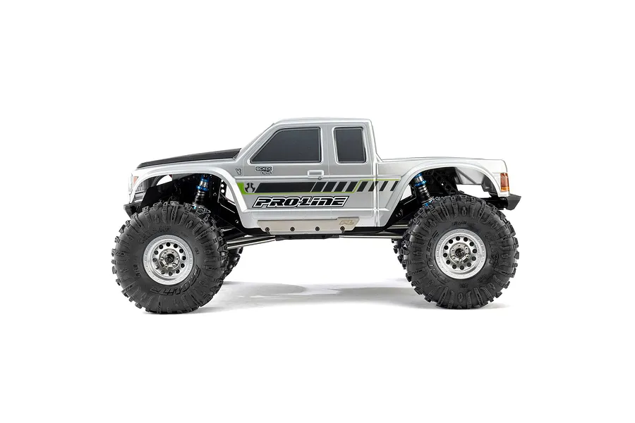 Side view of a silver RC crawler truck featuring Pro-Line Chisel II tyres mounted on beadlock wheels against a white background.