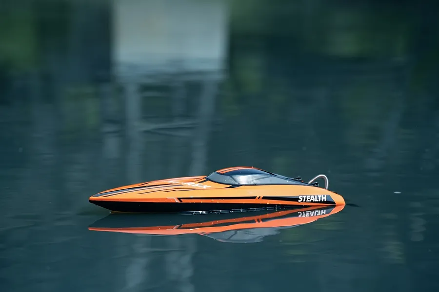 Atrek Stealth orange and black RC speed boat floating on calm water outdoors