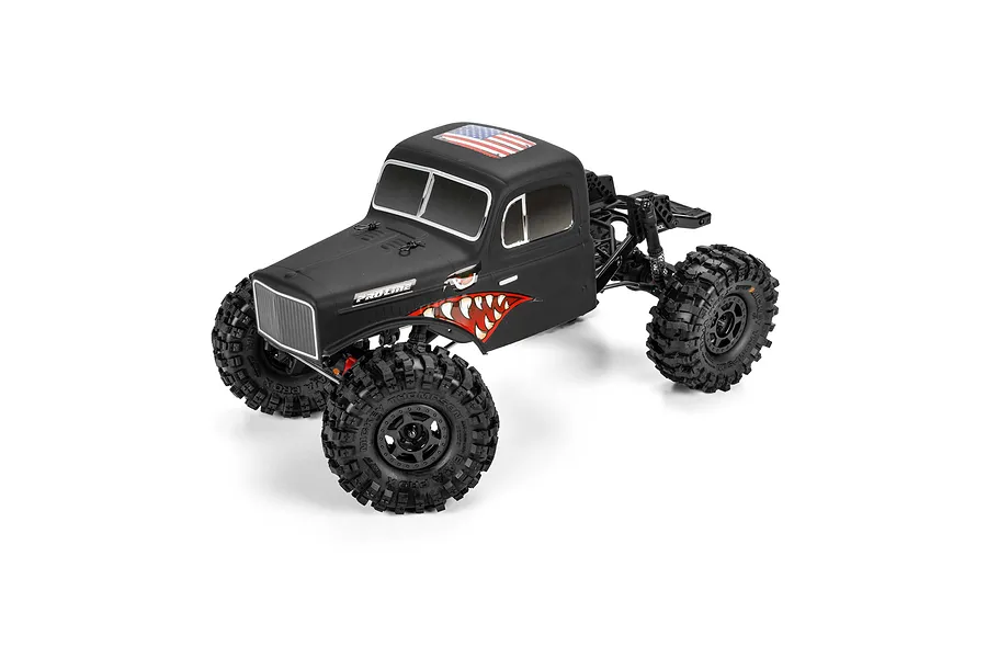 Pro-Line matte black cab-only crawler body mounted on an RC chassis with aggressive off-road tires and shark teeth graphics.