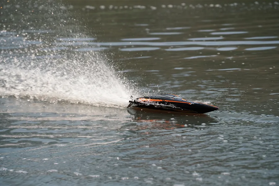 Atrek Stealth RC speed boat racing across the water, creating a large spray behind it.