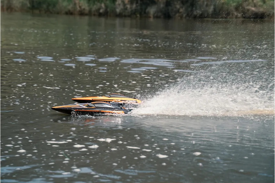Two Atrek Stealth RC speed boats speeding across open water, creating a large spray behind them.