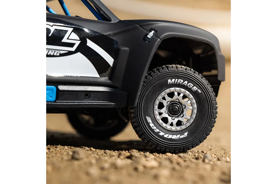 Close-up of matte black RC trophy truck body shell and front tire on a dirt surface