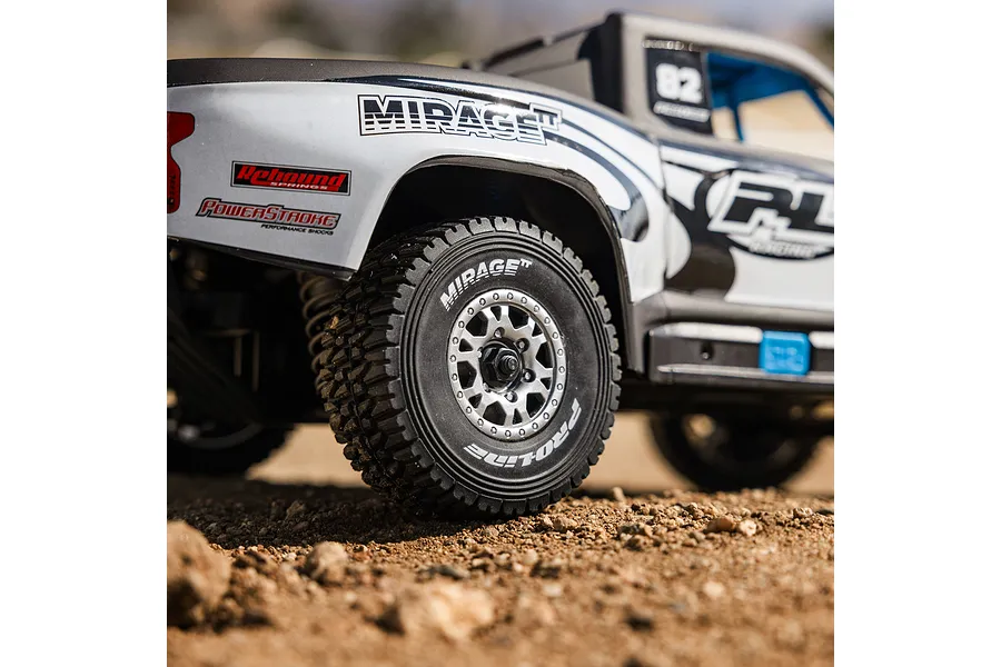 Close-up action shot of a Pro-Line RC trophy truck body shell and rear wheel on dirt terrain.