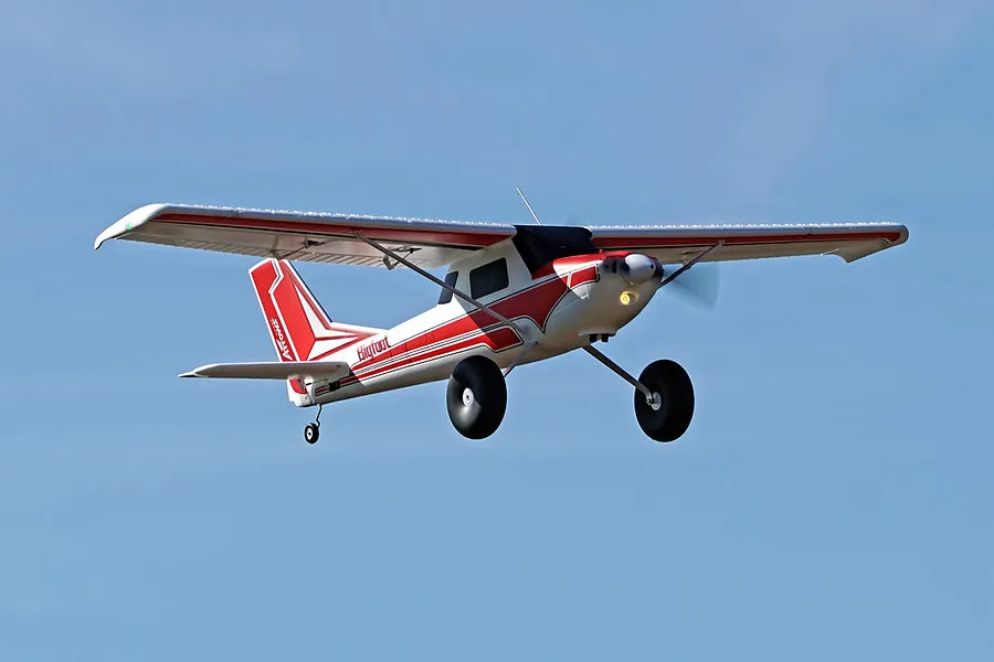 Arrows RC Bigfoot trainer airplane in flight against a clear blue sky background.
