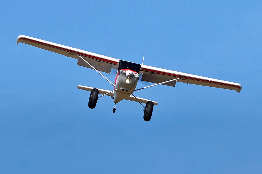 Arrows RC Bigfoot 1.3m trainer airplane flying against a clear blue sky in outdoor setting.