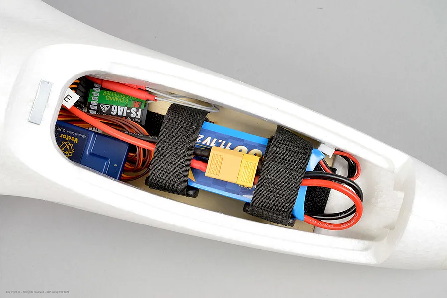 Top-down view of the internal electronics bay of the Arrows RC Prodigy trainer plane showing receiver, stabilizer, and battery.