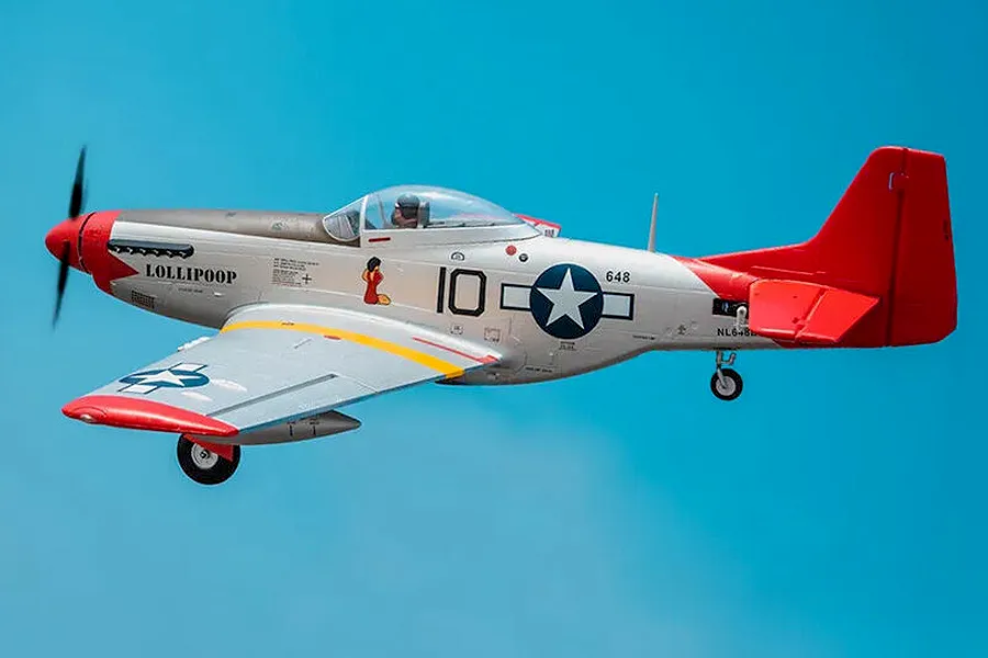 Arrows RC P-51 Mustang warbird airplane in flight against a bright blue sky background.