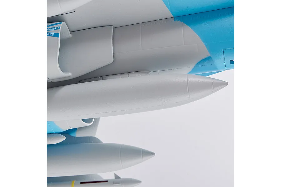 Close-up of the underside of the FMS F/A-18 Hornet RC plane showing molded panel lines, blue and grey camouflage, and mounted ordnance details against a white background.