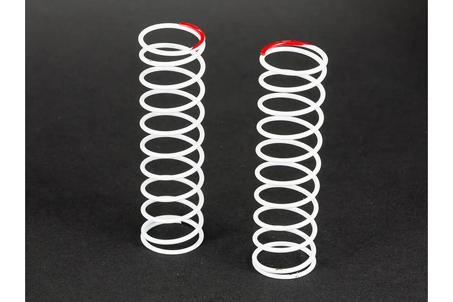 Two white ARRMA RC shock springs standing upright on a dark surface, each featuring a red paint mark on the top coil for identification.