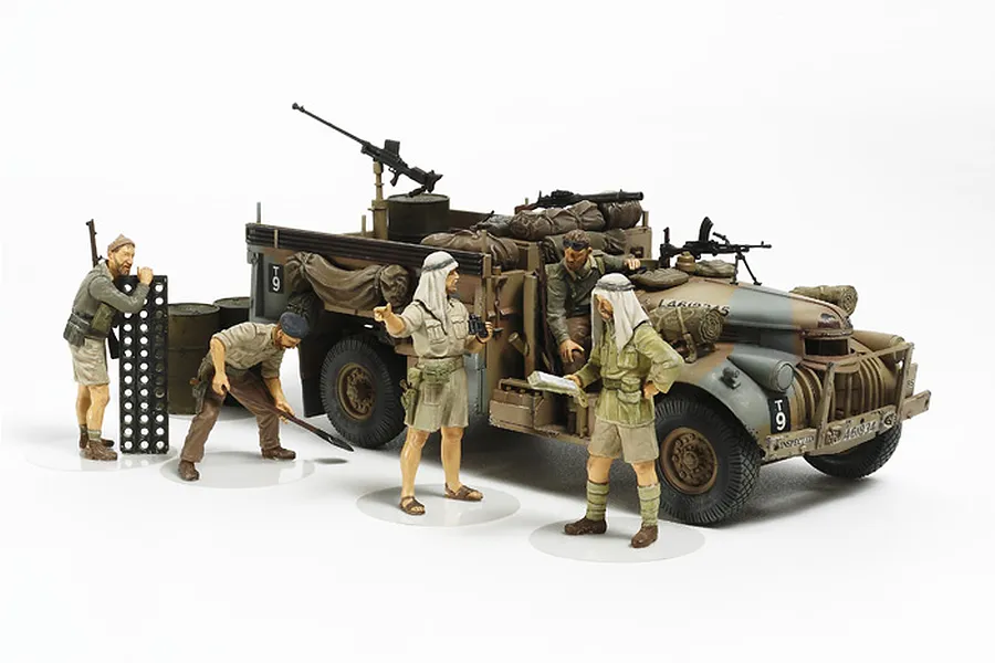 A completed 1/35 scale Tamiya LRDG Command Truck model kit with four painted soldier figures standing beside it on a white background.