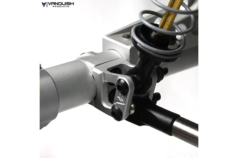Close-up of a silver aluminium Vanquish lower link and shock mount installed on an RC axle housing with a shock absorber and suspension link attached.
