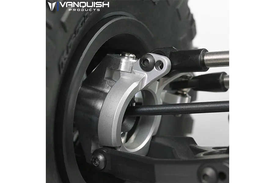 Close-up of a silver aluminium steering hub carrier installed on an RC vehicle, showing suspension linkages and part of the tire.